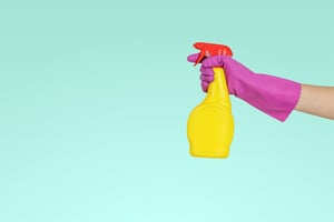 woman with pink rubber glove and yellow spray bottle.