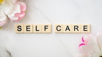 Self Care spelled out with letters pink flowers